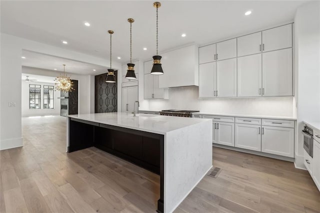 12632 Branyan Cir, Alpharetta, GA 30004 - kitchen with recessed lighting, light wood finished floors, white cabinetry, a center island with sink, and light stone counters