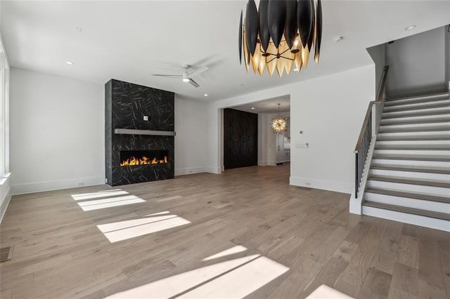 12632 Branyan Cir, Alpharetta, GA 30004 - unfurnished living room featuring stairs, wood finished floors, a premium fireplace, a chandelier, and ceiling fan