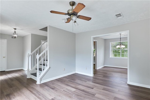 spare room featuring dark wood-type flooring and ceiling fan with notable chandelier