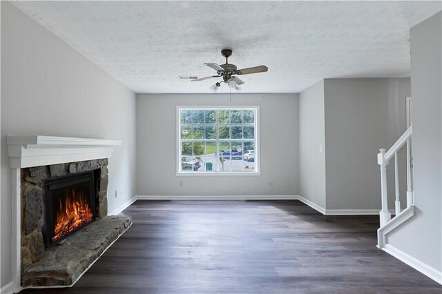 unfurnished living room featuring a textured ceiling, ceiling fan, dark hardwood / wood-style flooring, and a fireplace