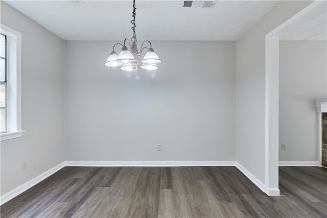 unfurnished room with dark wood-type flooring and an inviting chandelier