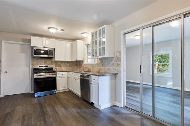 kitchen with dark wood-type flooring, backsplash, appliances with stainless steel finishes, and white cabinets