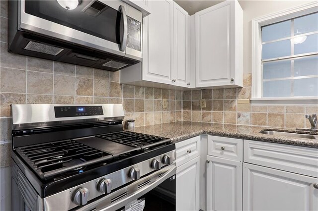 kitchen featuring stainless steel appliances, light stone counters, backsplash, and white cabinets