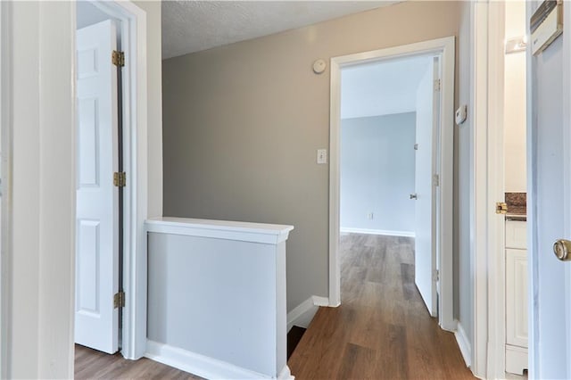 hall with hardwood / wood-style floors and a textured ceiling