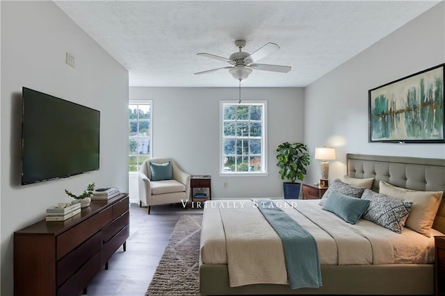 bedroom featuring dark hardwood / wood-style flooring, ceiling fan, and a textured ceiling