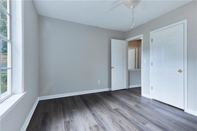 unfurnished bedroom with ceiling fan and dark hardwood / wood-style floors