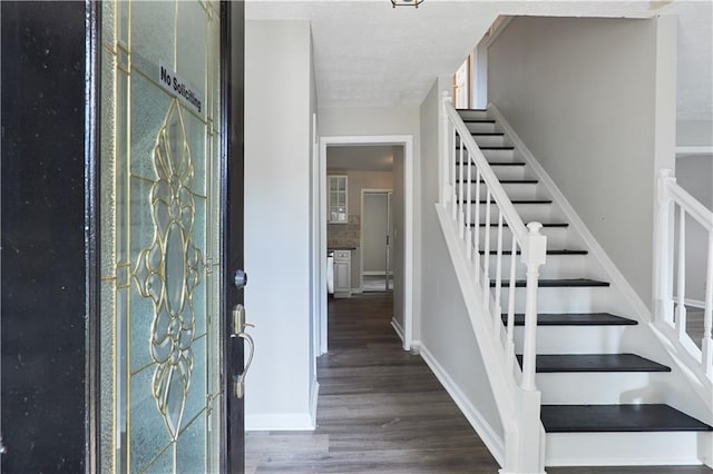 foyer entrance featuring a textured ceiling and dark hardwood / wood-style floors