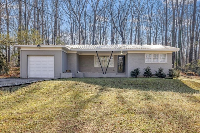 view of front of house featuring brick siding, a front lawn, metal roof, a garage, and driveway