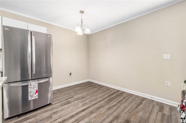 kitchen with wood finished floors, baseboards, freestanding refrigerator, white cabinetry, and crown molding