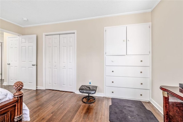 bedroom with a closet, baseboards, wood finished floors, and crown molding