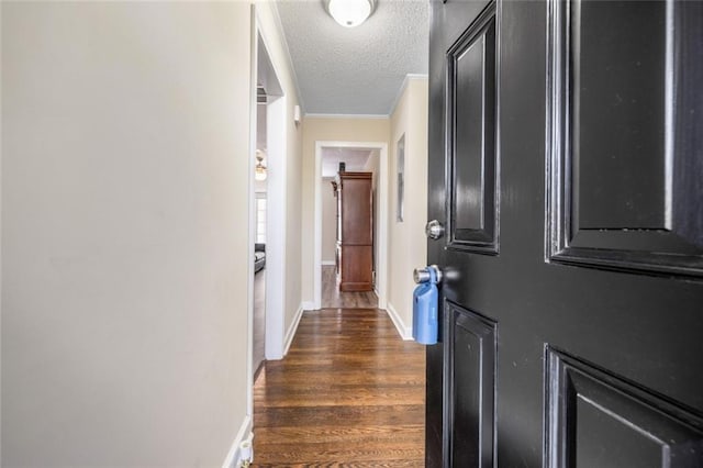 corridor featuring dark wood finished floors, crown molding, baseboards, and a textured ceiling