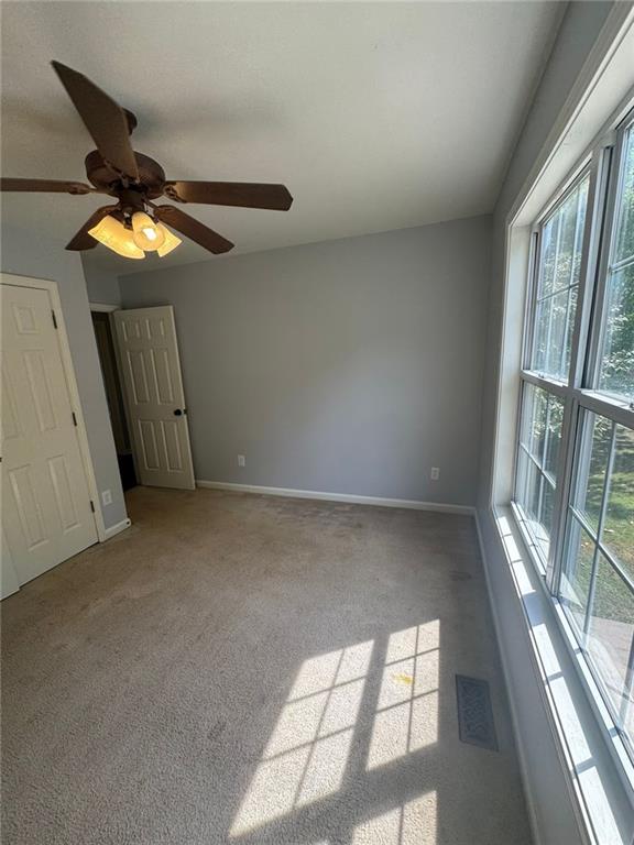 955 Tributary Way, Dacula, GA 30019 - unfurnished bedroom with multiple windows, carpet, and a ceiling fan