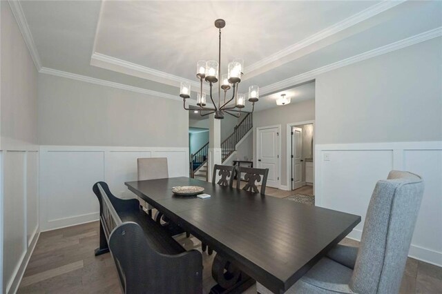 dining room featuring an inviting chandelier, crown molding, a raised ceiling, and hardwood / wood-style floors