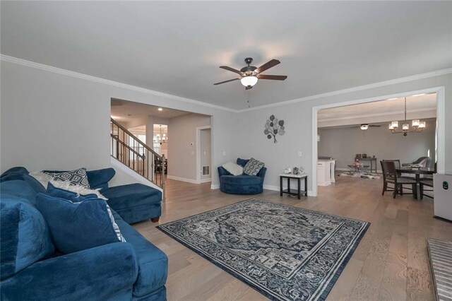 living room with hardwood / wood-style floors, ceiling fan with notable chandelier, and ornamental molding