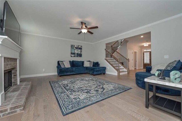 living room with a brick fireplace, ornamental molding, hardwood / wood-style floors, and ceiling fan