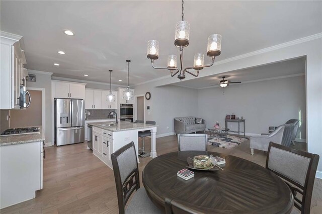 dining room with crown molding, ceiling fan, wood-type flooring, and sink