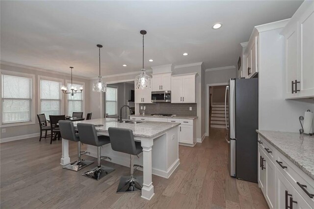 kitchen with sink, a center island with sink, appliances with stainless steel finishes, light stone countertops, and white cabinets