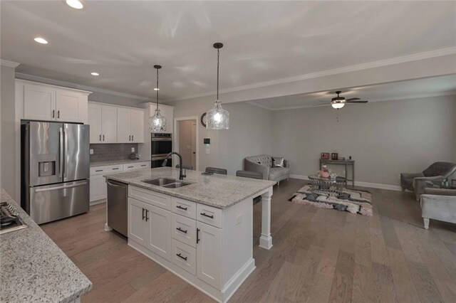 kitchen with sink, a center island with sink, stainless steel appliances, light stone countertops, and white cabinets