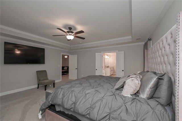 carpeted bedroom featuring a raised ceiling, ornamental molding, ensuite bathroom, and ceiling fan