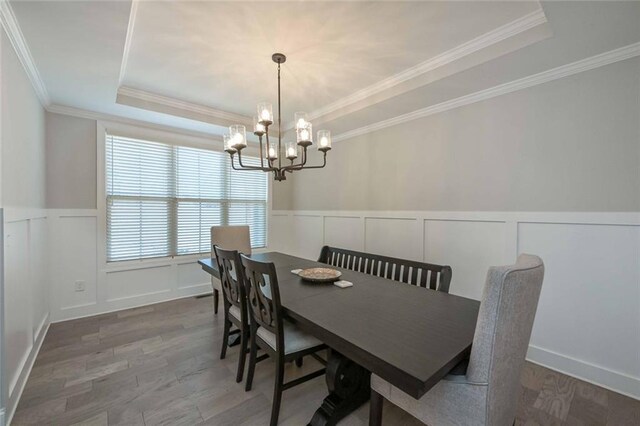 dining room featuring an inviting chandelier, ornamental molding, a tray ceiling, and hardwood / wood-style floors