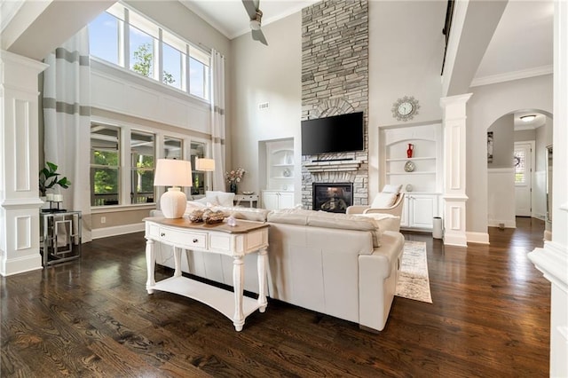 living room with arched walkways, a high ceiling, a fireplace, and decorative columns