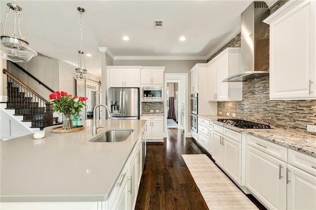 kitchen with wall chimney range hood, a center island with sink, a sink, stainless steel appliances, and recessed lighting