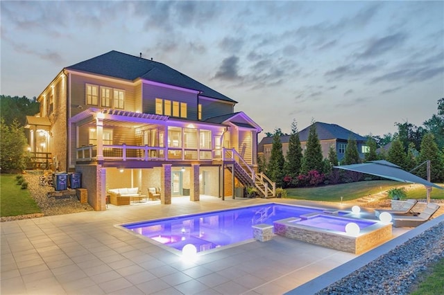 back of property with a patio, outdoor lounge area, a pool with connected hot tub, and stairway