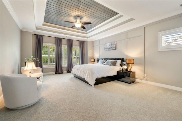 carpeted bedroom featuring baseboards, multiple windows, a tray ceiling, and ceiling fan