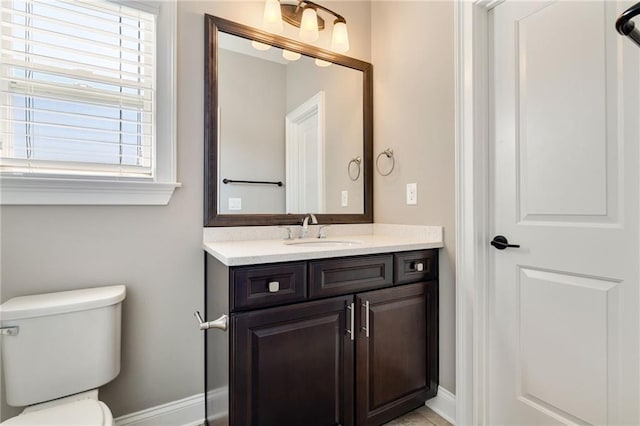bathroom with toilet, baseboards, and vanity
