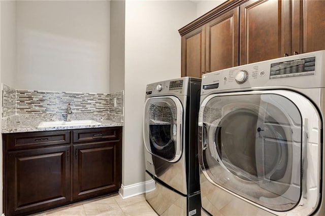 laundry area featuring a sink, baseboards, cabinet space, and washing machine and clothes dryer
