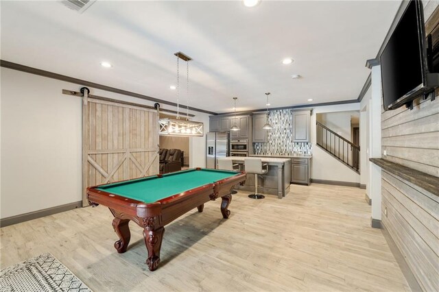 rec room with crown molding, baseboards, and a barn door