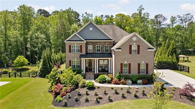 view of front of house with brick siding, a front lawn, fence, and a porch