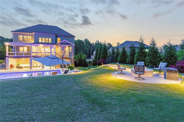 exterior space with a swimming pool, a balcony, a patio area, and an outdoor fire pit