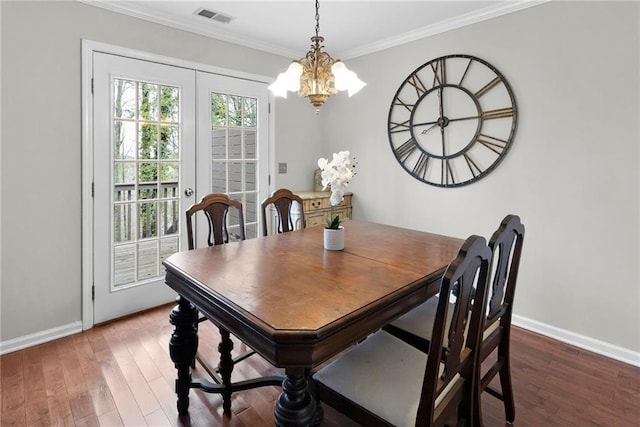 dining room with baseboards, crown molding, visible vents, and wood finished floors