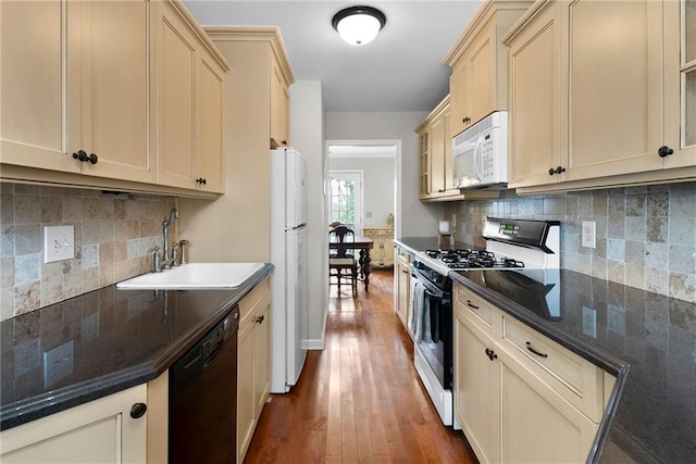 kitchen with white appliances, backsplash, dark wood-style flooring, and a sink