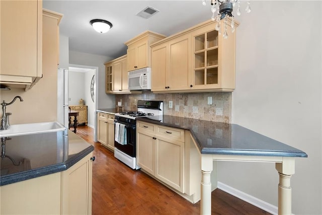 kitchen featuring white microwave, cream cabinets, a sink, visible vents, and range with gas cooktop