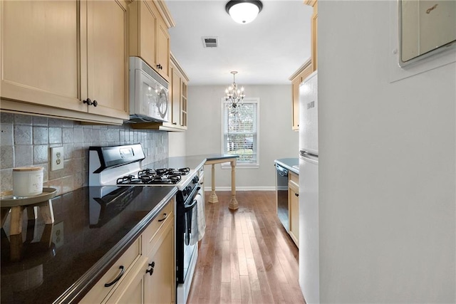 kitchen featuring tasteful backsplash, visible vents, dishwasher, white microwave, and gas stove