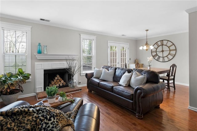 living room featuring visible vents, dark wood finished floors, a notable chandelier, and ornamental molding