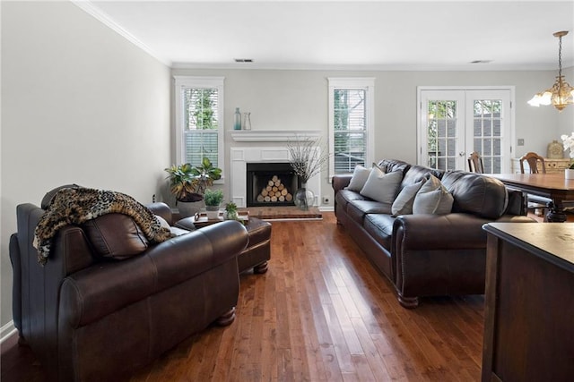 living area with a healthy amount of sunlight, dark wood-style floors, crown molding, and french doors