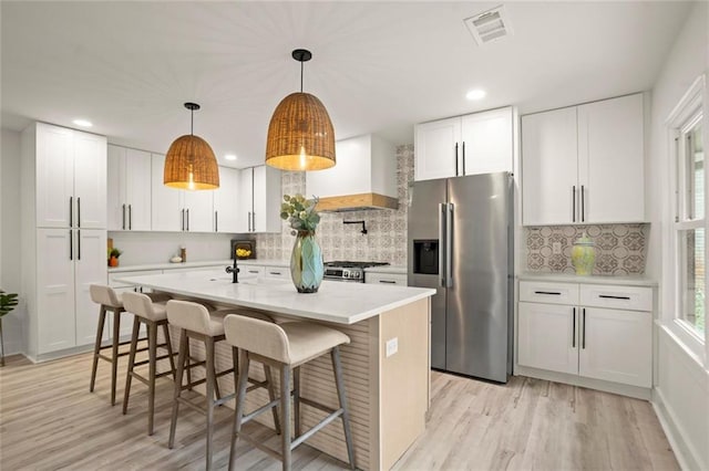 kitchen with premium range hood, light wood finished floors, visible vents, and appliances with stainless steel finishes
