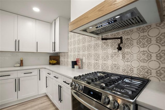 kitchen with white cabinetry, range hood, gas range, and light countertops