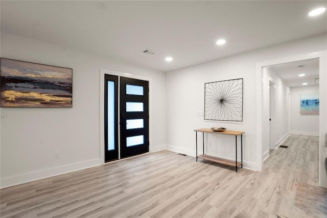foyer entrance featuring baseboards, visible vents, light wood finished floors, and recessed lighting