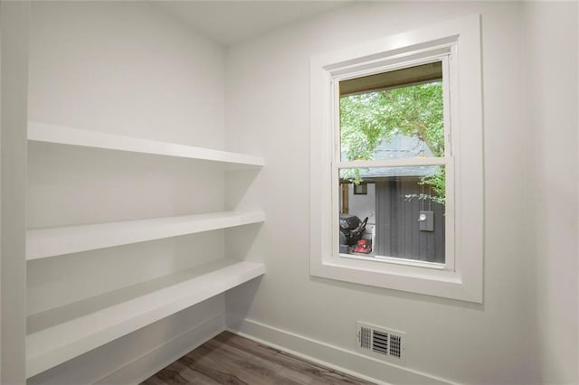 interior space with dark wood-style floors, visible vents, and baseboards