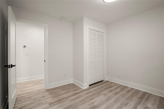 unfurnished bedroom featuring baseboards, light wood-style floors, and a closet