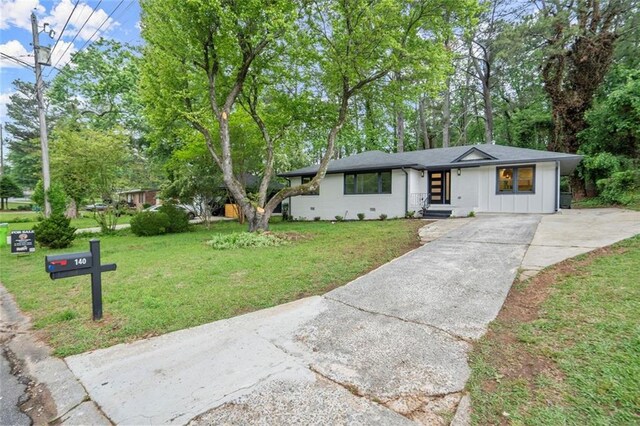 view of front of property featuring board and batten siding, driveway, and a front yard