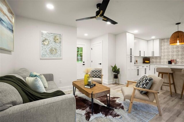 living area with recessed lighting, ceiling fan, light wood-style floors, and baseboards