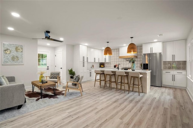 living room featuring baseboards, recessed lighting, a ceiling fan, and light wood-style flooring