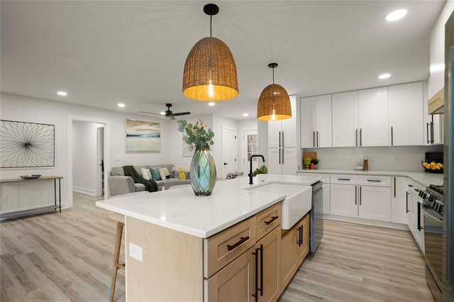 kitchen featuring recessed lighting, light wood-style floors, dishwasher, and a sink