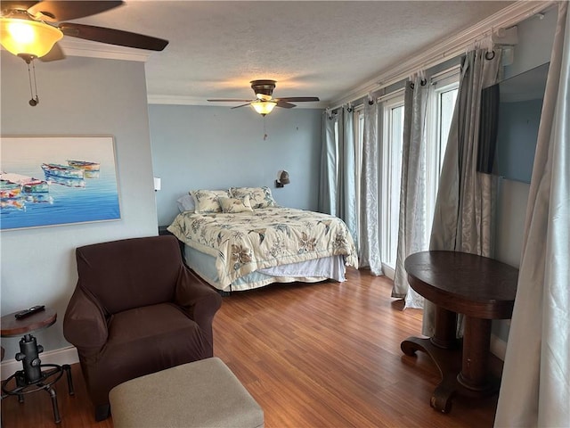 bedroom featuring ornamental molding, a ceiling fan, a textured ceiling, and wood finished floors