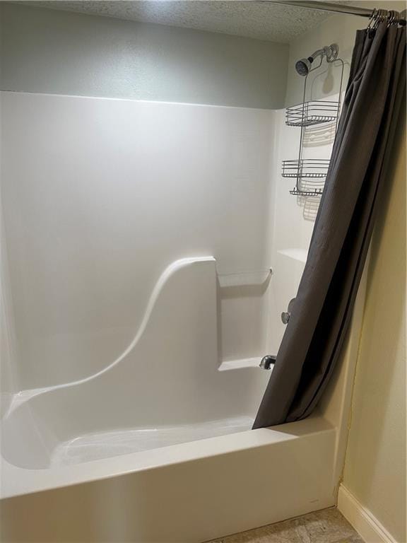 full bathroom with shower / tub combo with curtain, a textured ceiling, and baseboards